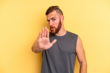 Young caucasian man isolated on yellow background rejecting someone showing a gesture of disgust.