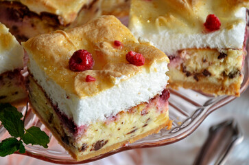 A piece of cheesecake with foam and raspberries
