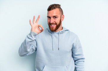 Young caucasian man isolated on blue background cheerful and confident showing ok gesture.