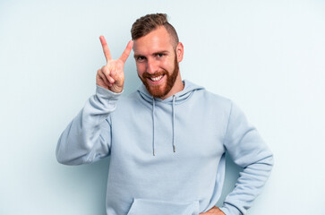 Young caucasian man isolated on blue background showing number two with fingers.