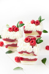 Mini cake in a cup with raspberry , delicious summer  dessert with fresh berries., portion dessert in a clear plastic cups. White wooden board, healthy eating , healthy dessert. Raspberry cake