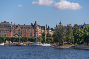 Fototapeta premium Bay view of boats at the district Östermalm with old apartment houses, a summer day in Stockholm, Sweden 2022-07-03