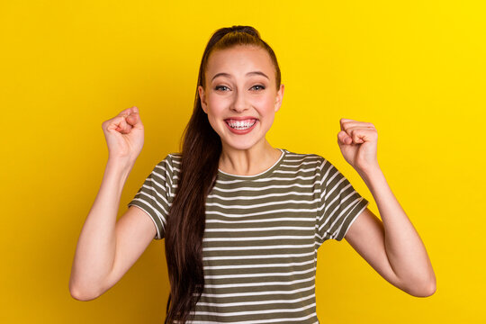 Excited young woman doing winner gesture celebrating clenching fist say yes isolated shine background studio portrait