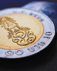 Translation: 10 baht Thailand. Thai coin lies on dark surface. Economy or finance. Loan and money....