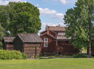 Obraz premium Old log farm houses with birch barks and wood tile roofs in a park, a summer day in Stockholm