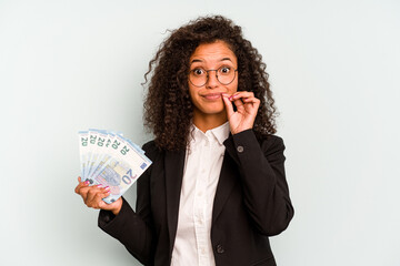 Young business Brazilian woman holding banknotes isolated on white background with fingers on lips keeping a secret.