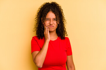 Young Brazilian woman isolated on yellow background having a strong teeth pain, molar ache.