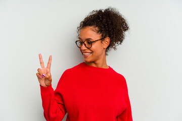 Young Brazilian woman isolated on blue background joyful and carefree showing a peace symbol with fingers.