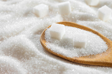 White granulated sugar and wooden spoon of refined sugar close-up