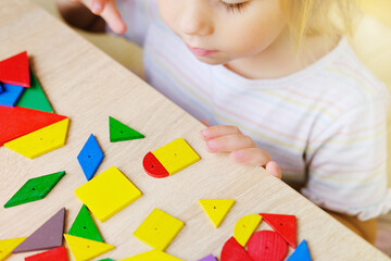 cute child, girl 3 years old plays with colored wooden geometric figures, counts details, concept...
