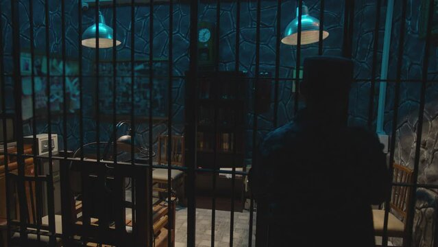 Dark jail cell at night . Hanging Swaying swinging lamps on dark room . Silhouette of policeman opening Interrogation room before interrogating . Prison life concept . Shot on camera ARRI slow motion