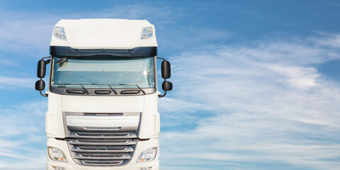 Front view of a large white cargo truck in front of a blue sky