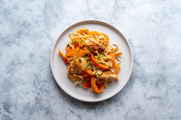 Stir fry noodles with chicken meat and vegetable, grey background. Asian style food, homemade food