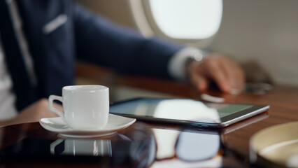 Hand taking coffee cup in luxury airplane closeup. Successful manager resting