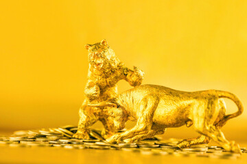 Bear and bull fighting over bitcoins against golden background. Market trend concept.