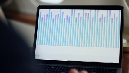 Closeup laptop finance chart on airplane. Business analyst hands typing computer