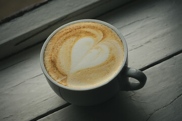 Cup of cappuccino with a heart near the window