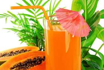papaya fruit and glass of juice and exotic leaves