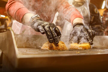 Chef making and grilling burger buns on an electric grill.