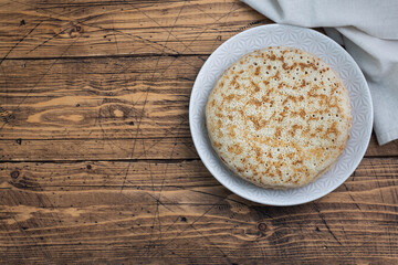 Thin pancakes on a plate, top view, wooden background. The concept of a delicious breakfast or Maslenitsa. copy space