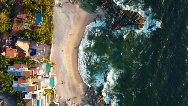 top down view of beautiful white sand rocky beach at Playa Amapas in Puerto Vallarta Mexico at sunset, aerial