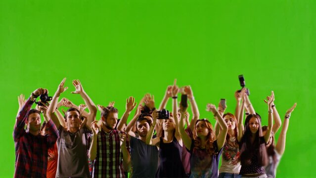 Group of young people or fans dancing , jumping and having fun on green screen. You can install different backgrounds of public place , concert stadium , disco clubs . Shot on RED camera . slow motion