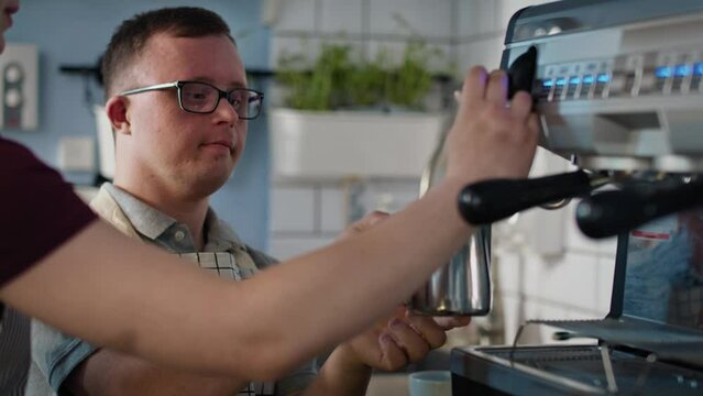 Caucasian man with down syndrome as a waiter helping waitress in making coffee. Shot with RED helium camera in 8K.
