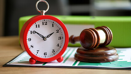 Judges gavel with alarm clock on financial documents