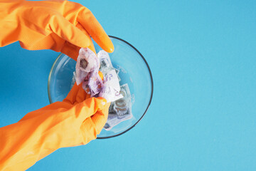 hands in orange gloves wash money with soap on a blue background