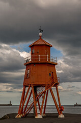 The old, red, wooden Herd Groyne Lighthouse in South Shields, stands out against the cloudy sky
