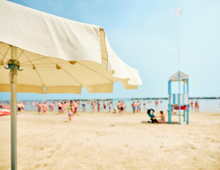 View of the beach from an umbrella with a lifeguard tower alongside a lifeboat on the beach on a...