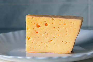 Piece cheese on white plate.