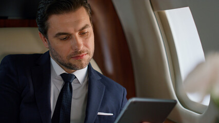 Successful manager tapping tablet in plane closeup. Focused ceo using computer