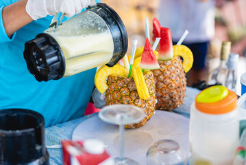 Horizontal image of an unknown person preparing delicious pineapple cola drinks on a summer day. 