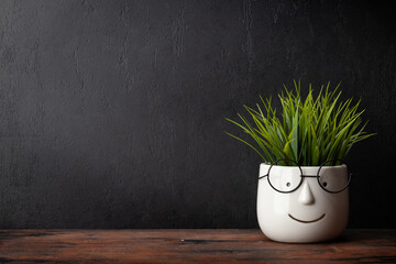Potted plant with glasses on table and blackboard