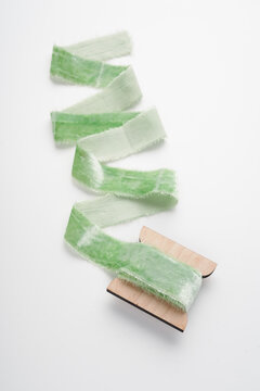 Velvet light green ribbon on a spool lies on a white background with a curl. Decorative ribbons for decorating bouquets