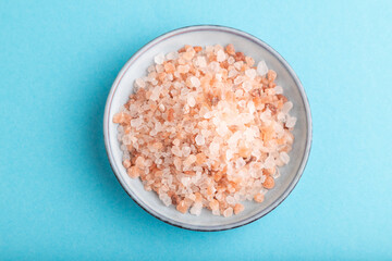 plate with pink Himalayan salt on blue pastel. top view, close up.