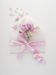 Fototapeta na wymiar Romantic letter. A message with pink flowers and an envelope with a pretty ribbon on a white background