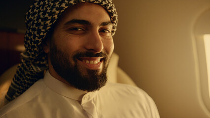 Smiling arabic man posing at airplane window closeup. Happy businessman travel