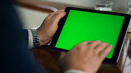 Closeup green tablet screen in luxury office. Man hand swiping mockup device