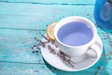 Cup of aromatic lavender tea with a pile of lavandula flowers, lemon and honey, top view on blue wood table copy space