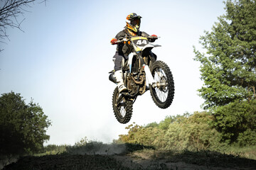 Live shot of male sportsman training on motorbike at hot summer day, outdoors. Motocross rider in...