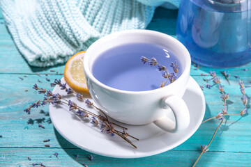 Cup of aromatic lavender tea with a pile of lavandula flowers, lemon and honey, top view on blue wood table copy space