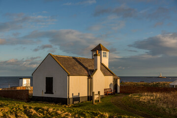 The old Watch House on the cliffs above Seaton Sluice in Northumberland, England at sunset.