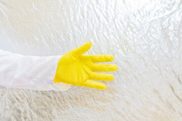 A doctor in a medical gown and protective gloves holds out his hand for a handshake. The face is not visible.