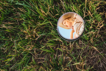 Reflection of woman in a mirror on grass