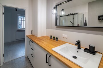 Modern bathroom with a wash basin, a wooden countertop and white furniture