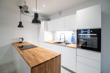Modern kitchen with a dining area and a counter. White and wooden furniture