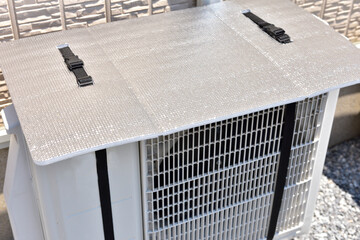 エアコンの室外機に保護カバーをつけて冷房効率アップ。節電対策のコンセプト。