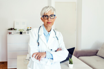 Portrait of a confident and mature doctor folding her arms. Portrait of a smiling mature female doctor standing in her office.